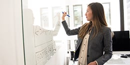 woman-wearing-gray-blazer-writing-on-board-260px